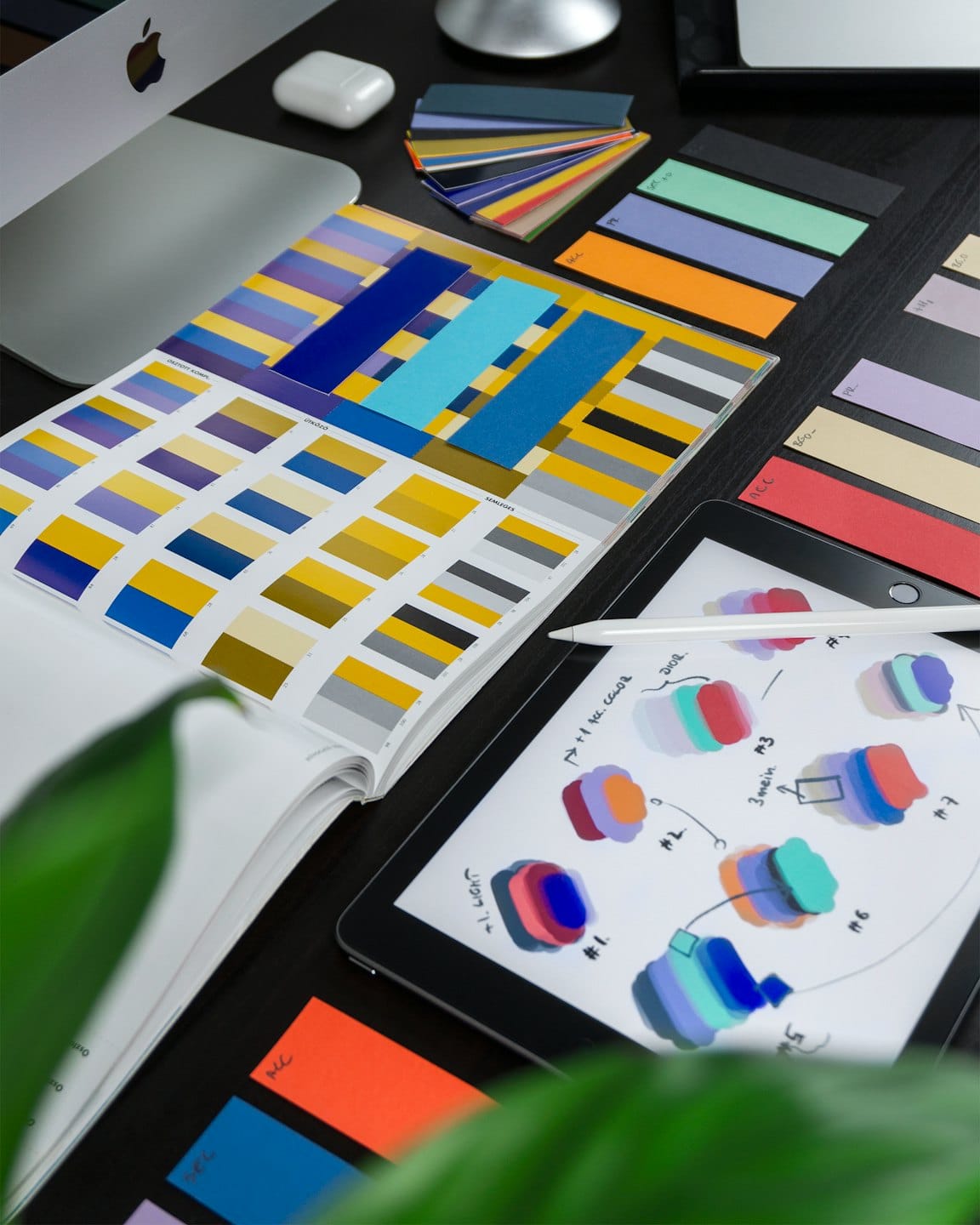 Designer's desk with color swatches, iPad, and Apple Pencil.
